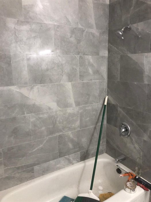 Grey marble-look tile surround with new shower fixtures