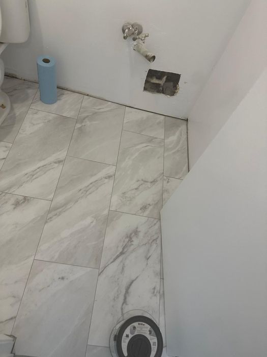 Marble-look floor tile being set in a powder room