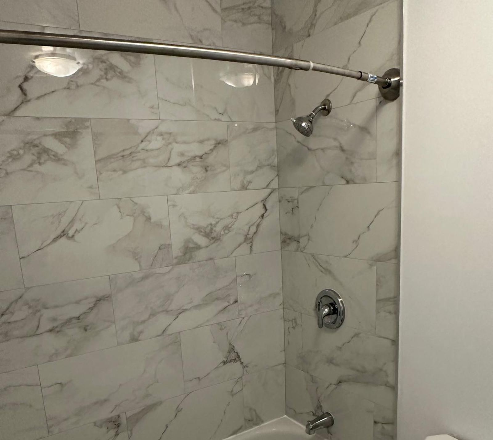 Newly tiled bathroom with marble-look porcelain tile and chrome fixtures, completed by Worry Free Construction